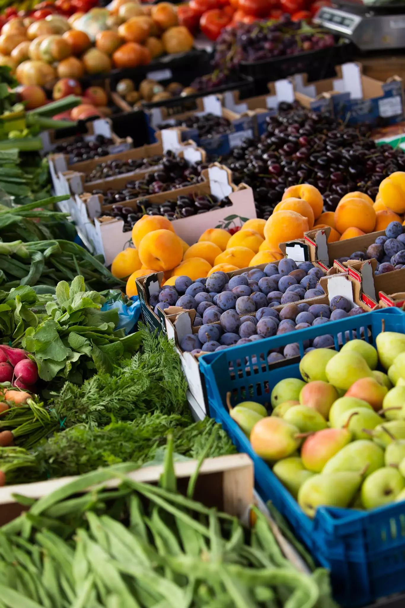 Fruits et légumes frais assortis présentés dans des caisses sur un marché.