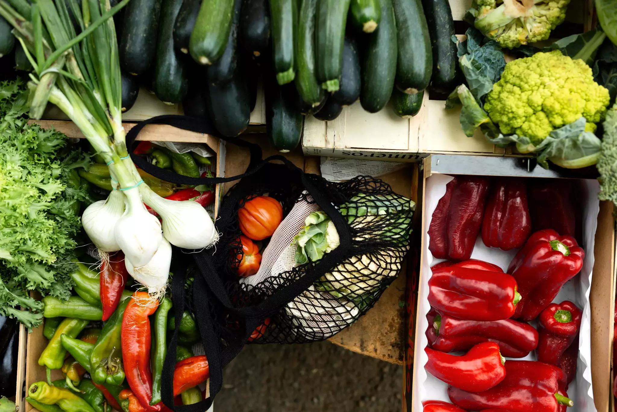 Légumes frais assortis présentés sur un étal de marché, dont des courgettes, des poivrons et des choux-fleurs.