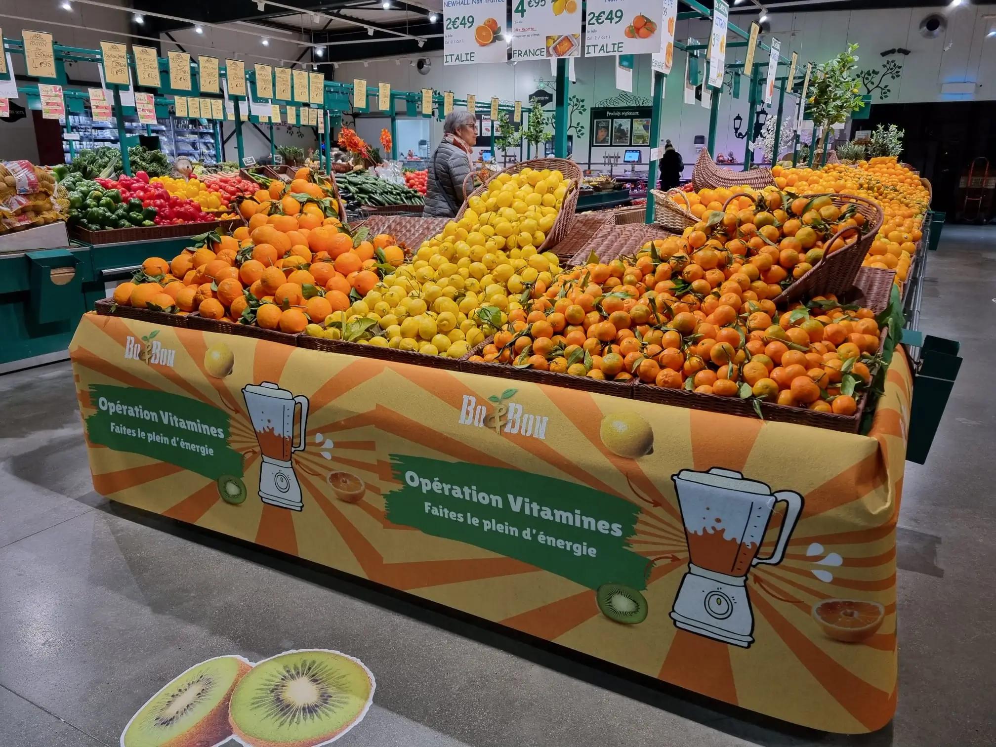 Un étalage vibrant de divers agrumes dans une épicerie avec des bannières promotionnelles.