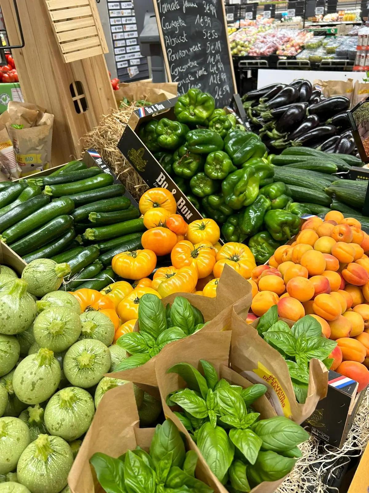 Un étalage d'épicerie coloré avec divers légumes frais comme des poivrons, des courgettes et des tomates.