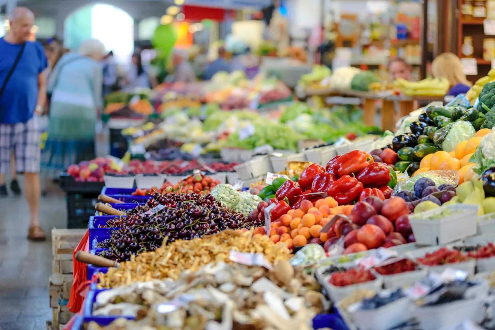 Marché de fruits et légumes frais en plein air avec des étals colorés, où des producteurs locaux vendent leurs produits