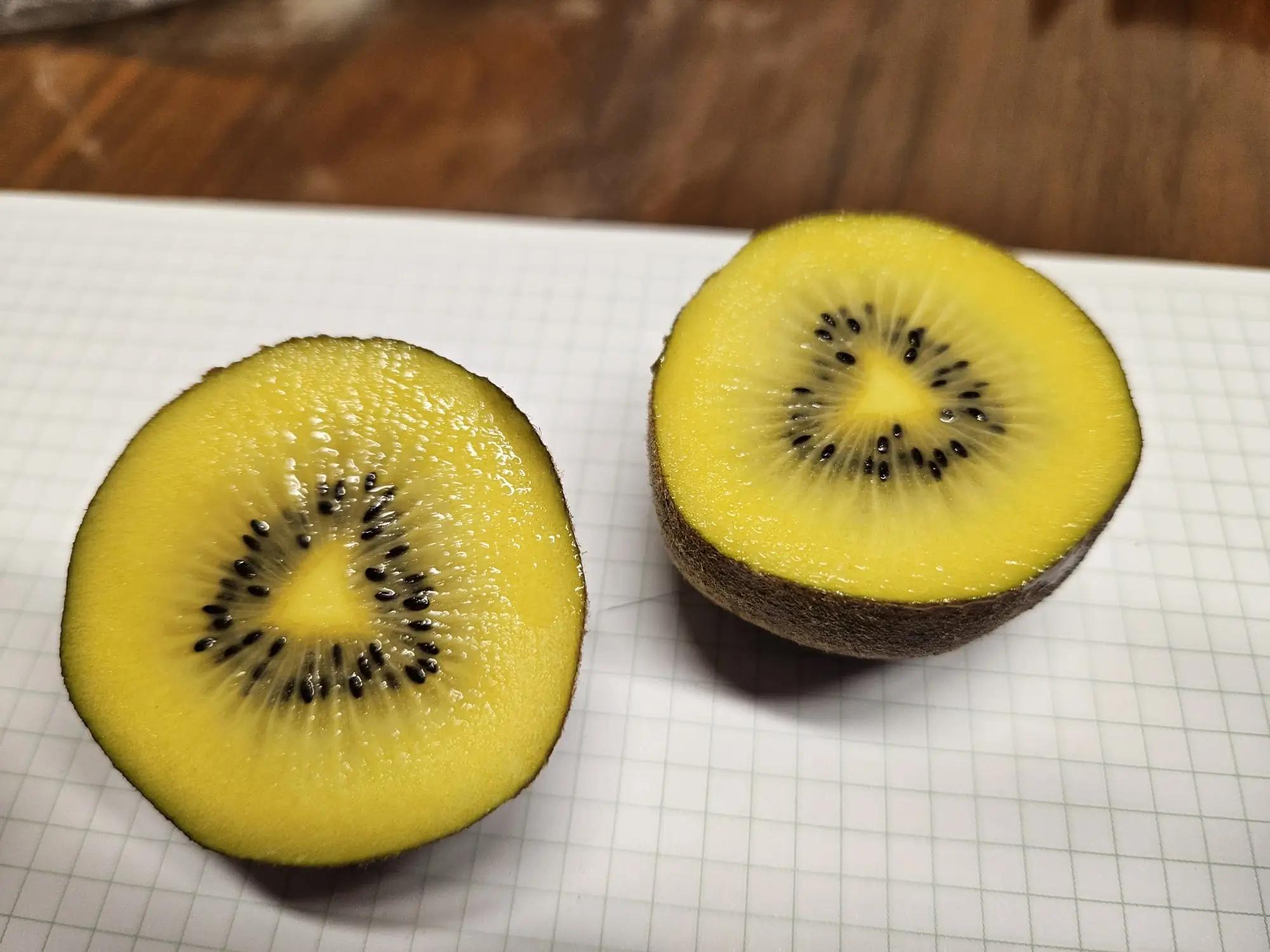 Deux moitiés de kiwi jaune sur un papier quadrillé.