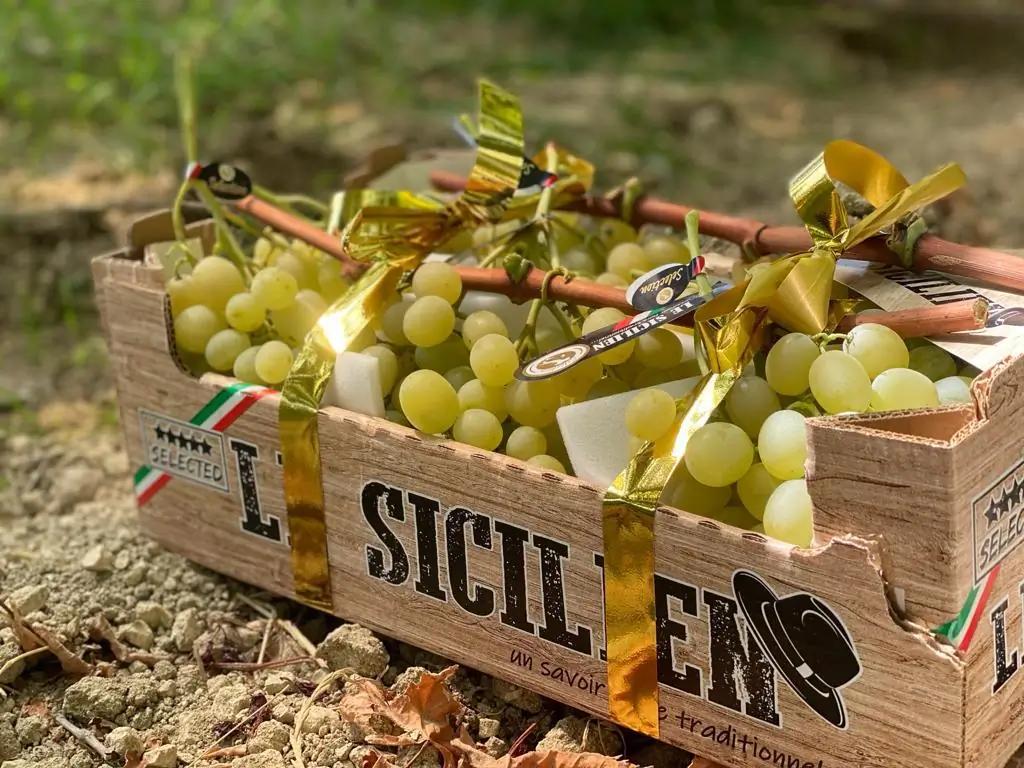 Caisse en bois remplie de raisins blancs, marquée « SICILIAN », sur fond naturel.